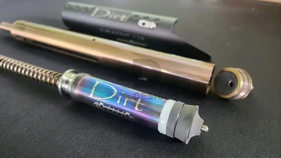 Close-up of the Edgi Custom Works Jurassic VSR-10 kit – heat-treated iridescent cylinder and 'Dirt' SAP shock-absorbing piston with spring guide, for Tokyo Marui VSR-10